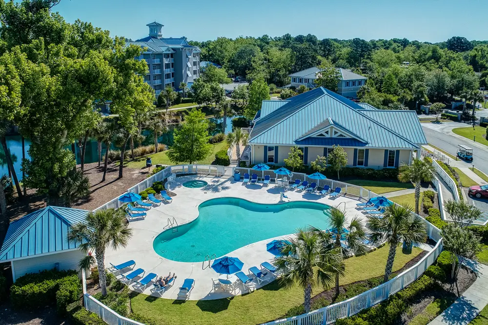 Expansive lagoon-style pool with lazy river, hot tub, and blue umbrella loungers at Bluewater Resort by Spinnaker Resorts, Hilton Head Island, South Carolina.